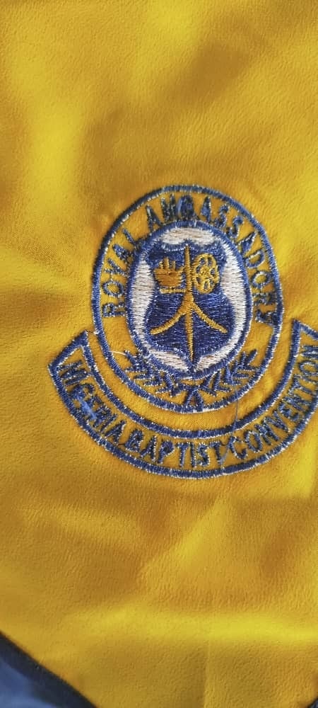 A club badge on yellow fabric where the curved lettering has broken up, with the yellow showing through the blue stitching